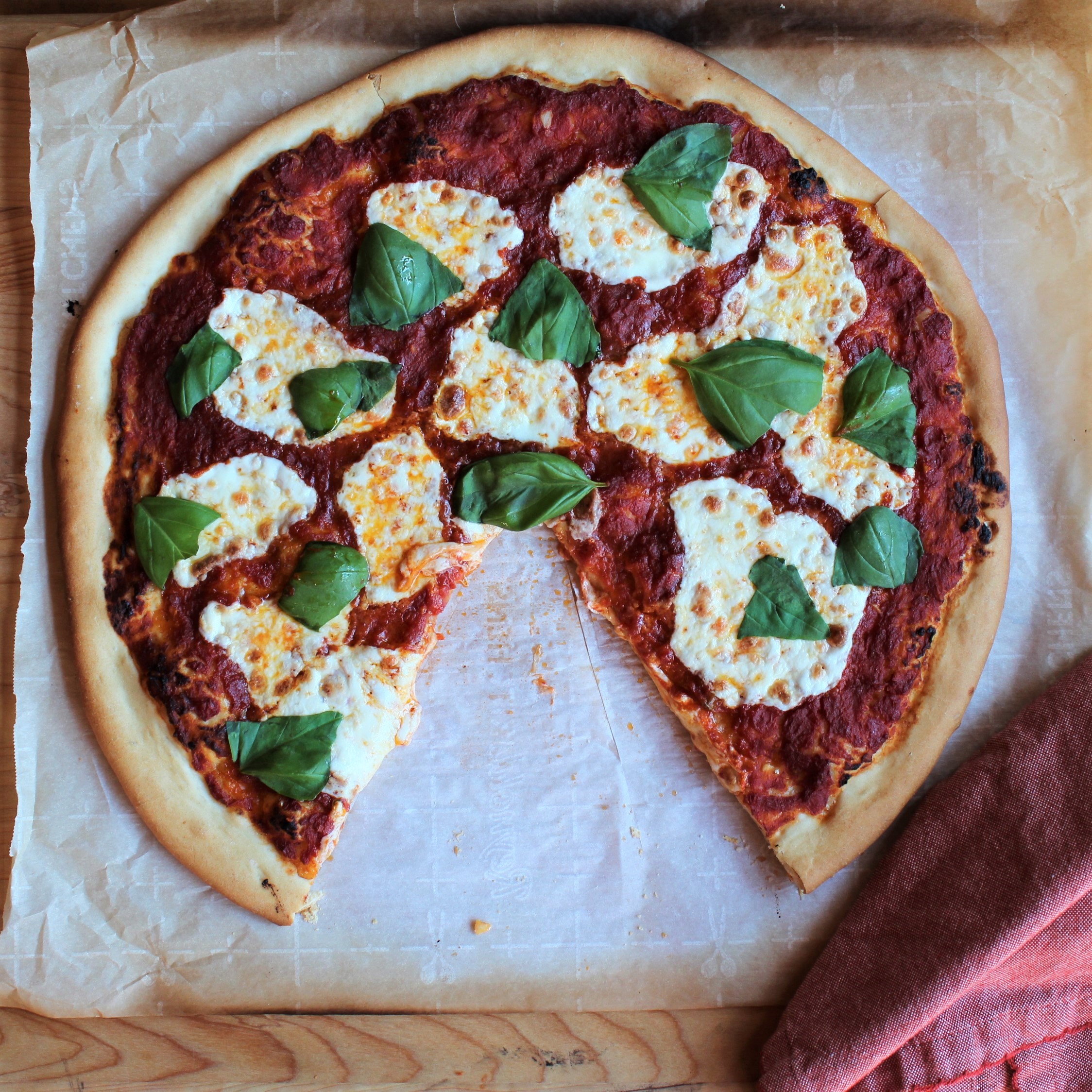 A pizza margherita  with a piece cut out. 
