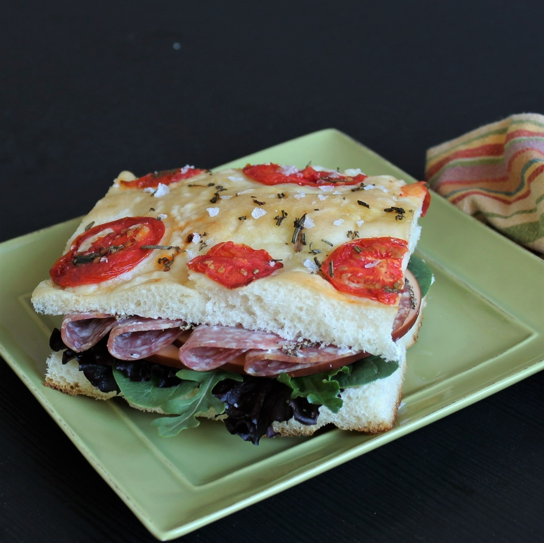 A focaccia sandwich on a square green plate
