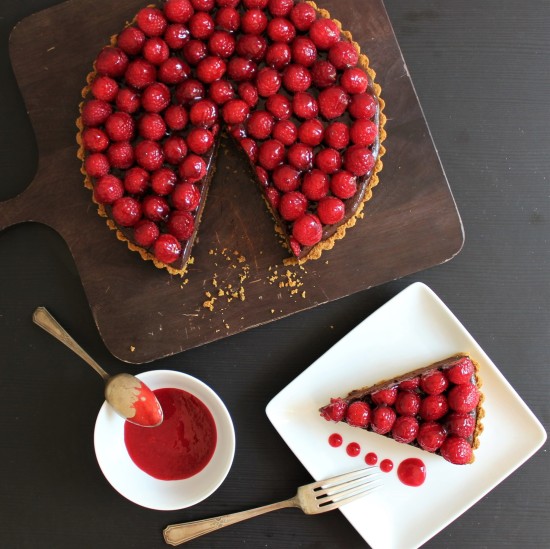 A chocolate raspberry tart with a slice on a plate