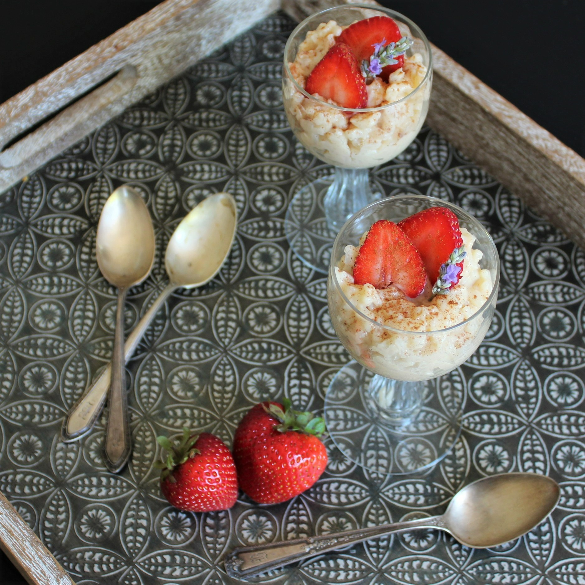 Two antique dessert glasses of rice pudding with strawberries and spoons