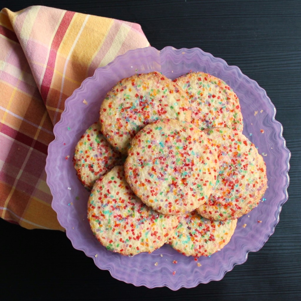 sugar cookies decorated with colored sugar on a pink plate