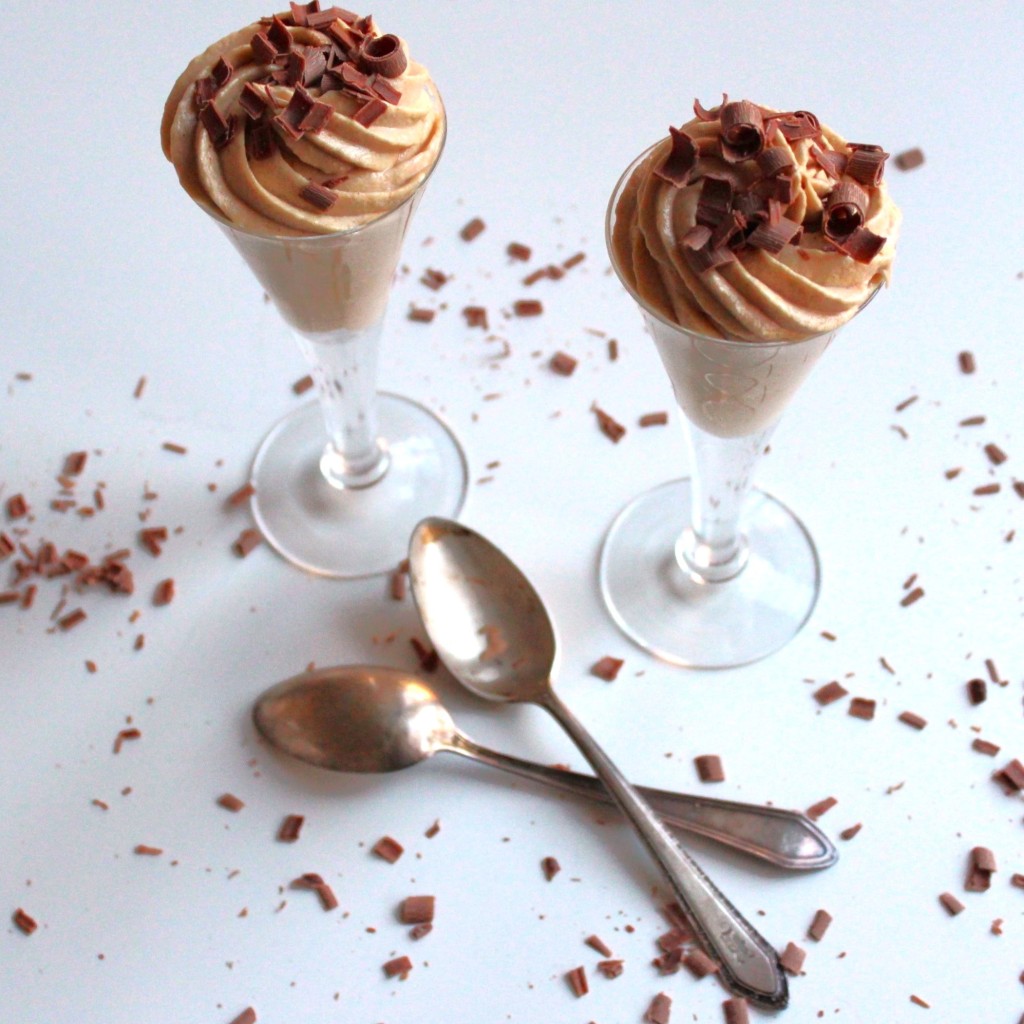 Two peanut butter mousee parfaits with spoons and scattered chocolate